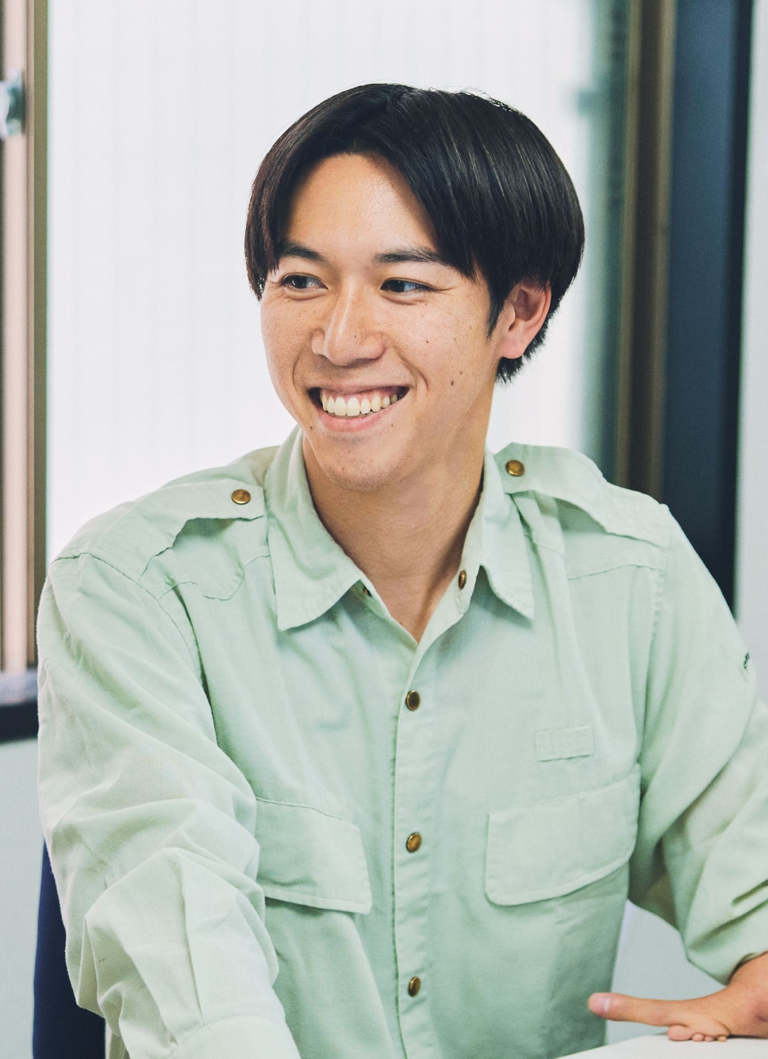 現場の事務所にて上肢障がいをもつ社員の階戸健太さんが同僚と談笑している様子